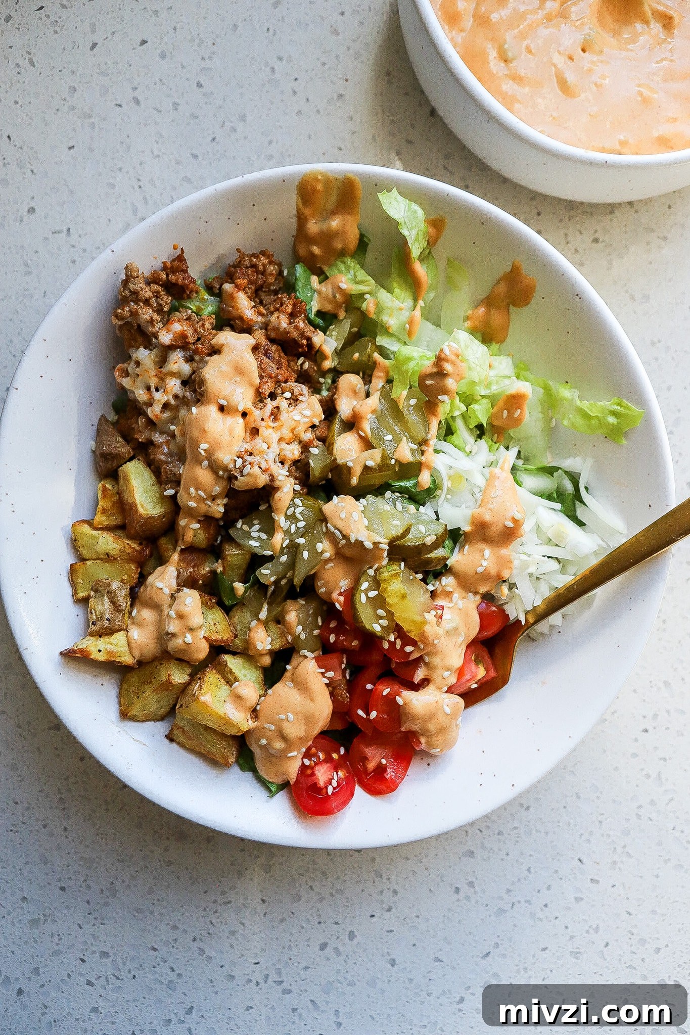 Top down view of a healthy burger bowl with a gold fork sticking out.