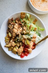 Top down view of a healthy burger bowl with a gold fork sticking out.