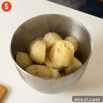 Garlic Parmesan Mashed Potatoes Recipe — Creamy Comfort Side Dish 8 Softened and boiled potatoes in a mixing bowl.