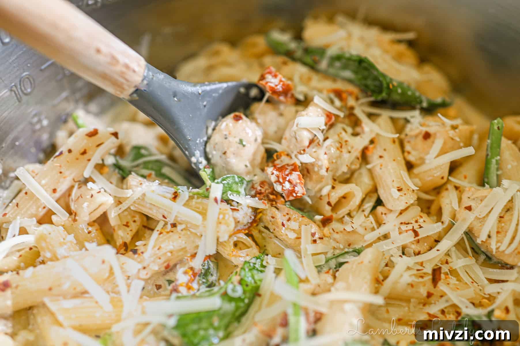 scooping a spoonful of marry me chicken pasta.