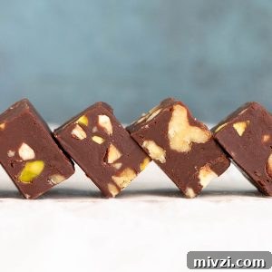 Quick Microwave Chocolate Fudge: Ready in Minutes 11 White surface and blue background with squares of chocolate nut fudge leaning into each other.