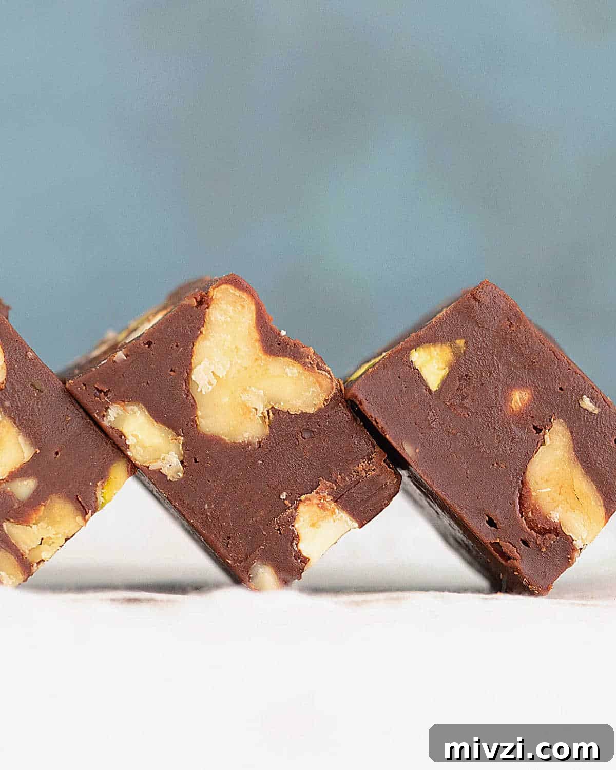 Quick Microwave Chocolate Fudge: Ready in Minutes 3 Close up of chocolate walnut fudge pieces on a white surface with a blue background.
