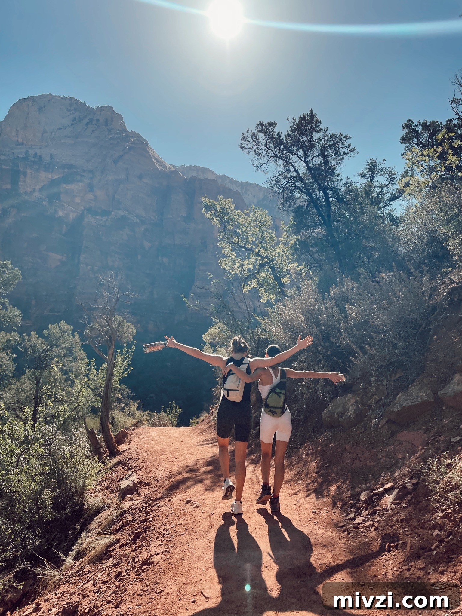two girls with their arms around their back walking into the sun orb