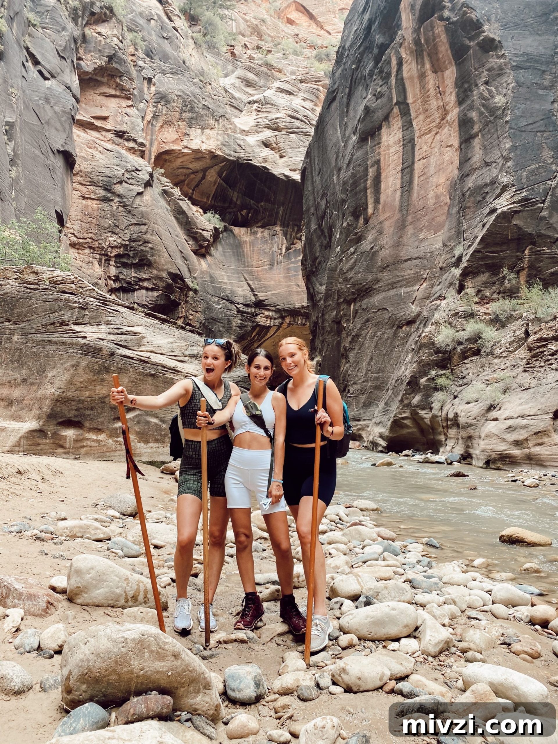 three girls with hiking sticks in the middle of the Narrows in Zion National Park