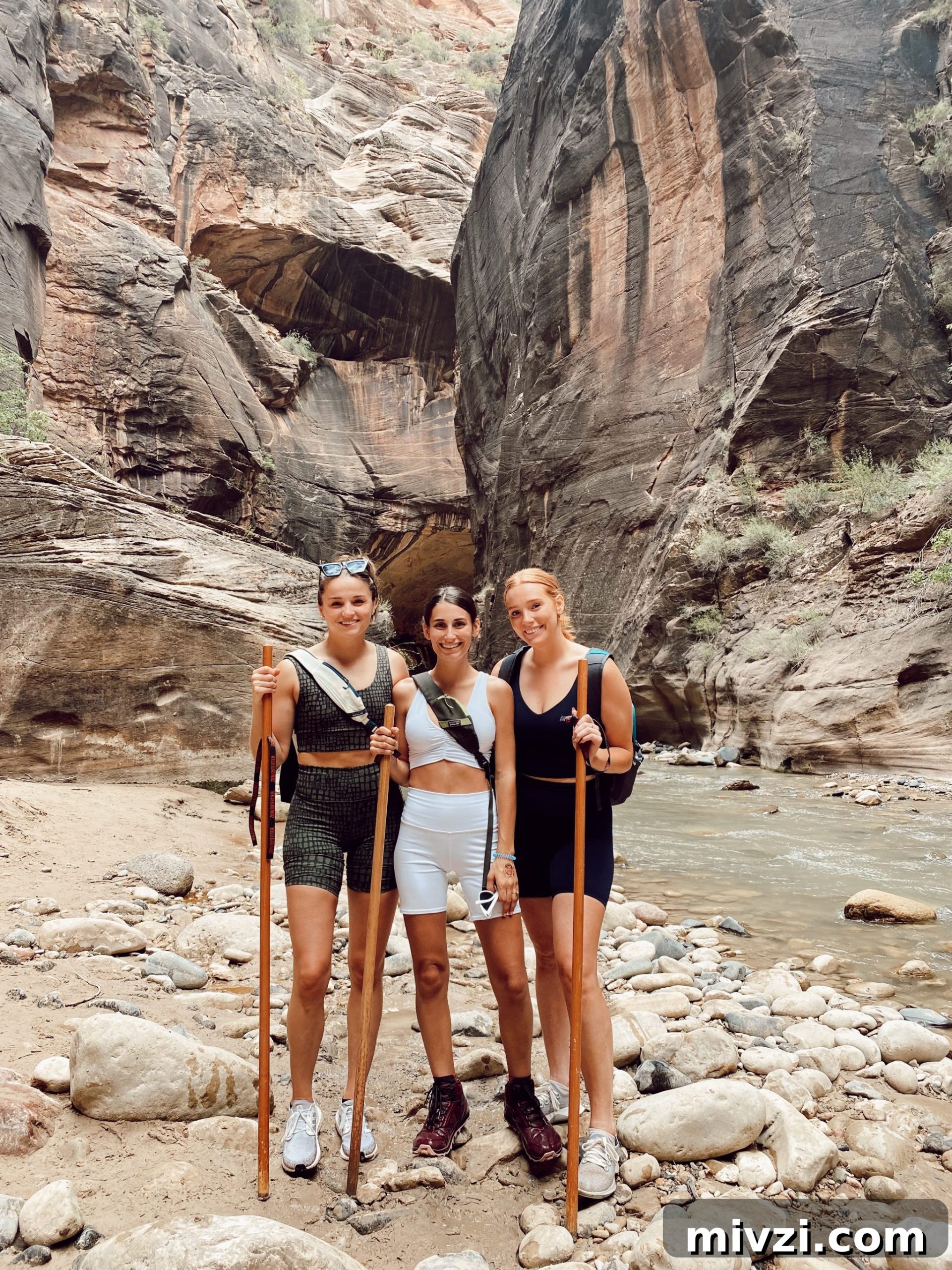 three girls with hiking sticks in the middle of the Narrows in Zion National Park