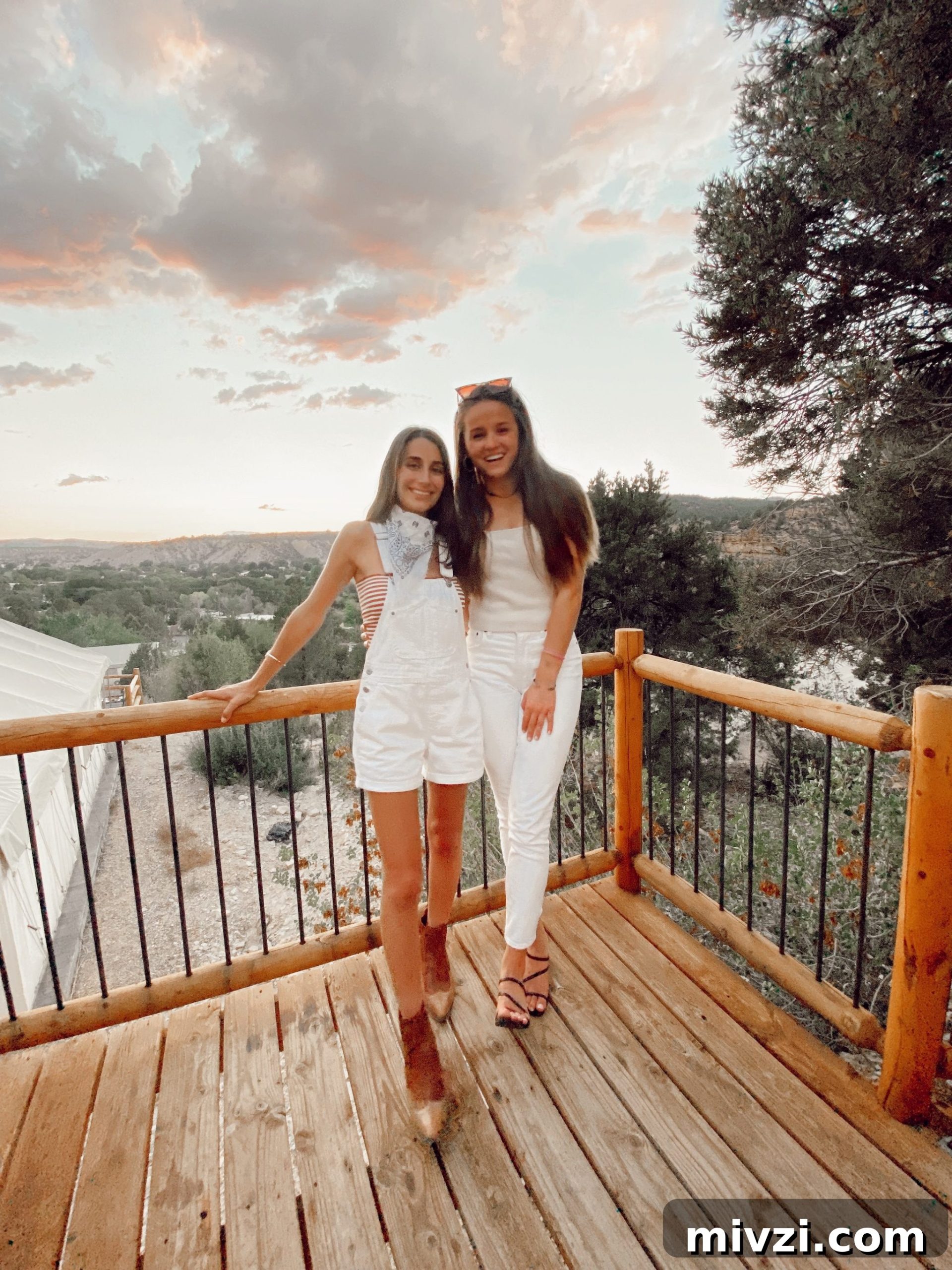 two girls standing on a deck overlooking the sunset