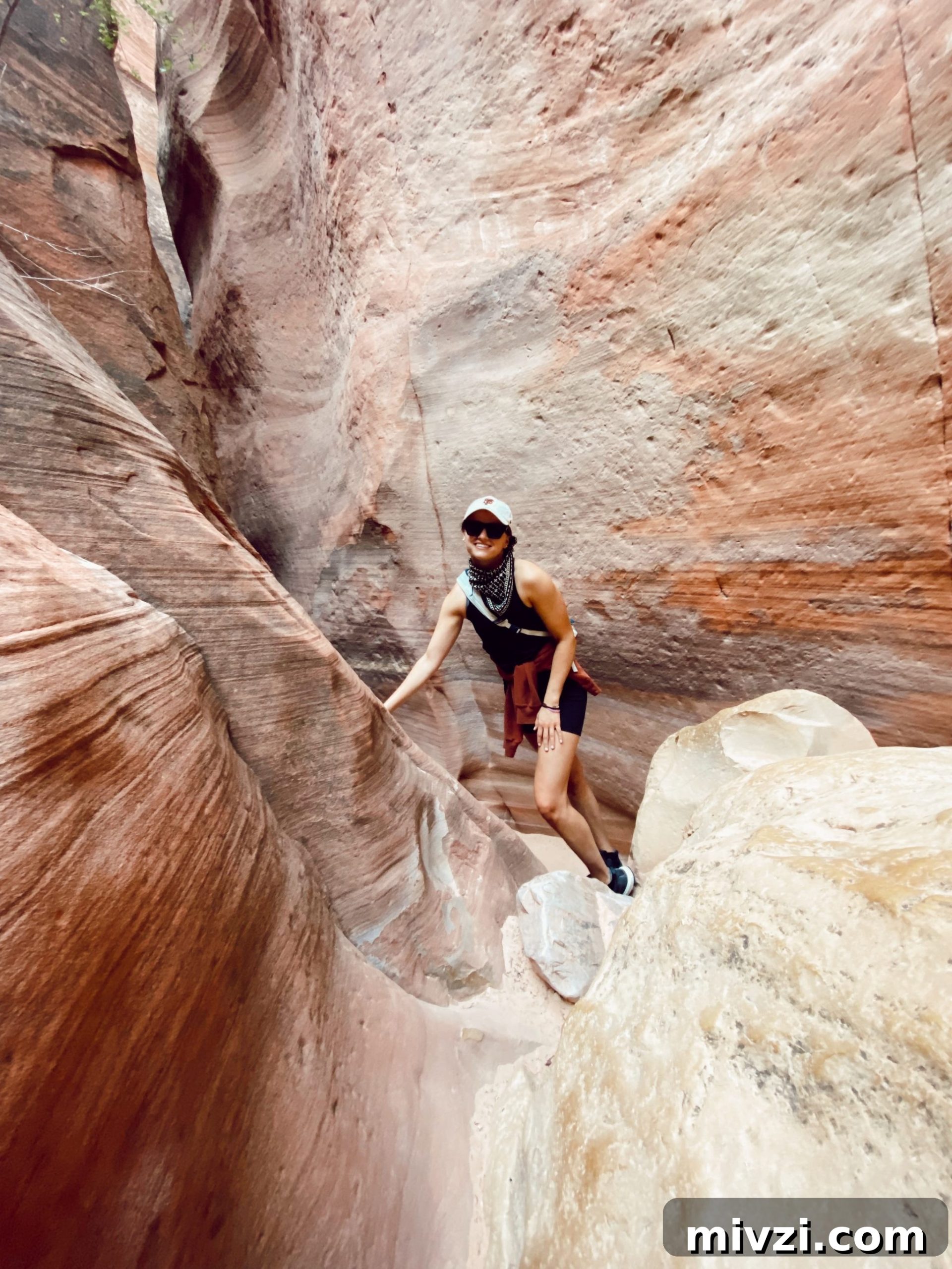 girl hiking in the middle of two mountains with her hand rested on a large rock