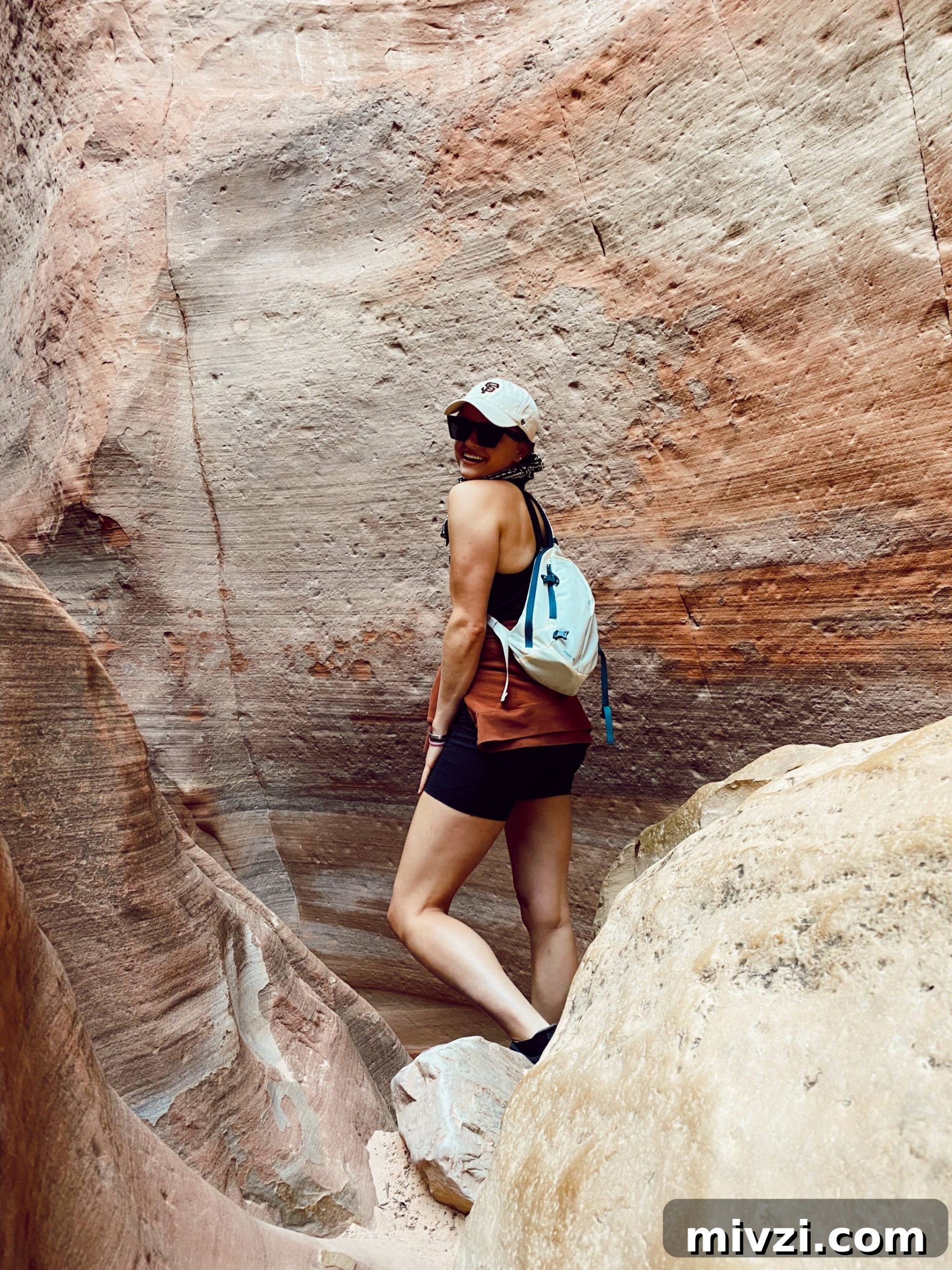 girl standing in front of a mountain cave smiling