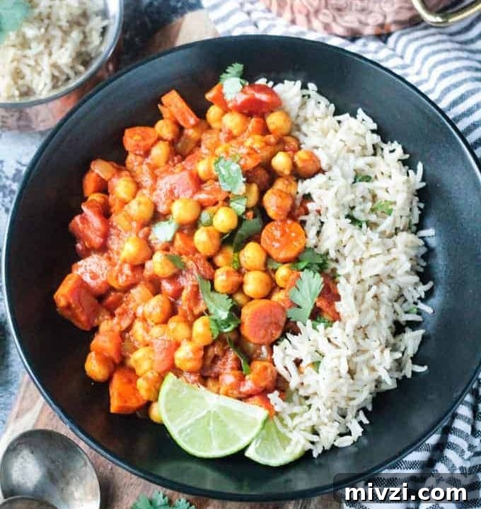 Overhead view of a black bowl of spiced chickpea stew and brown rice.