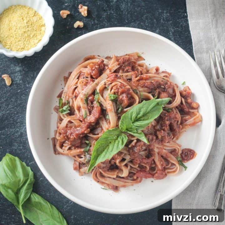 Fettuccine noodles with vegan bolognese garnished with fresh basil leaves.