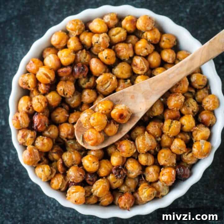 Seasoned roasted chickpeas in a bowl with a small wooden spoon.