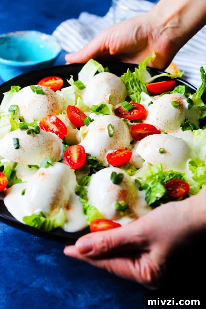 Serving Eggs Mayonnaise on a black serving plate with scallions and cherry tomatoes