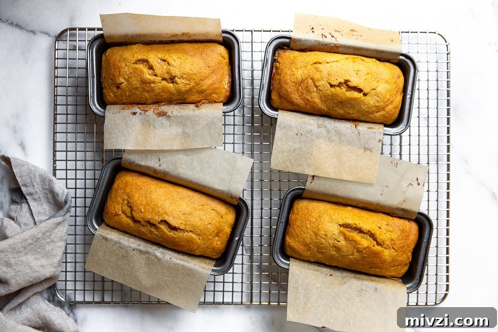 Pumpkin Pound Cake with Bourbon Cream Cheese Frosting рецепт 6 Four mini pumpkin pound cakes in baking pans on a cooling rack.