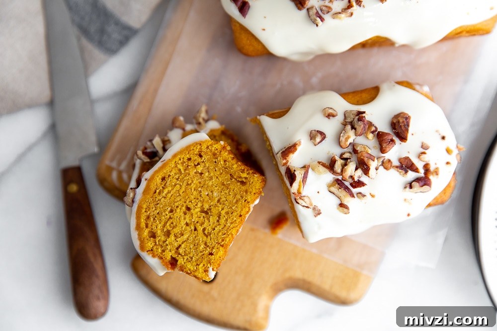 Pumpkin Pound Cake with Bourbon Cream Cheese Frosting рецепт 8 Overhead shot of a slice of pumpkin cake on a wooden serving board with a knife alongside.