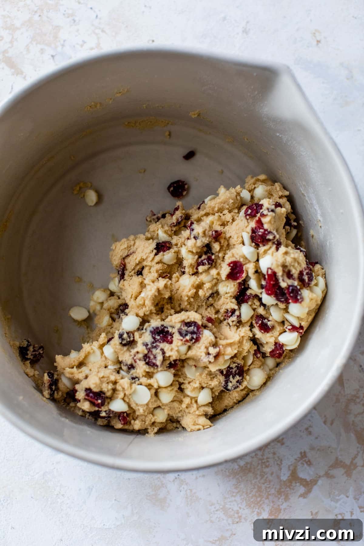 cookie dough in a large bowl with cranberries added in