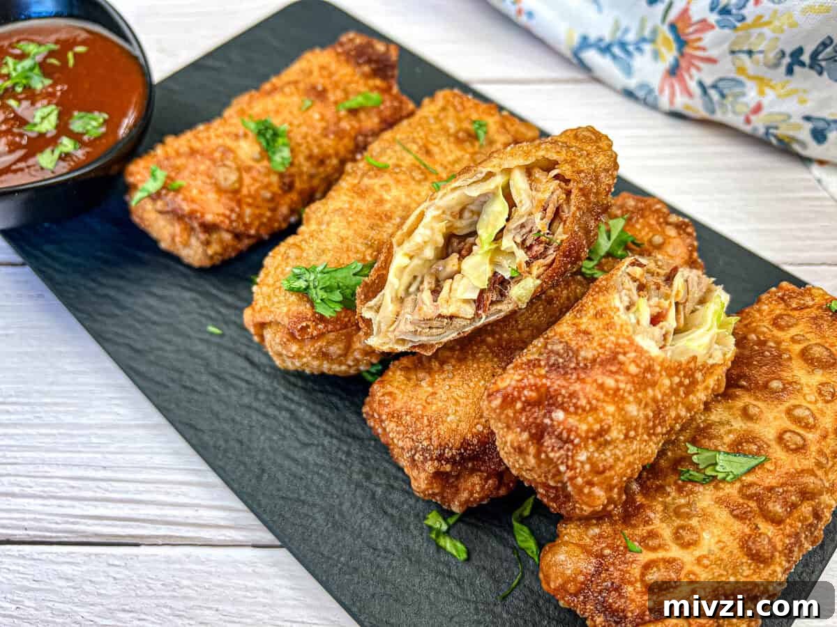 37 Winter Olympics Dishes to Warm Cold Nights and Long Broadcasts 14 Redneck Eggrolls on a black slate garnished with chopped herbs and a small bowl of dipping sauce.