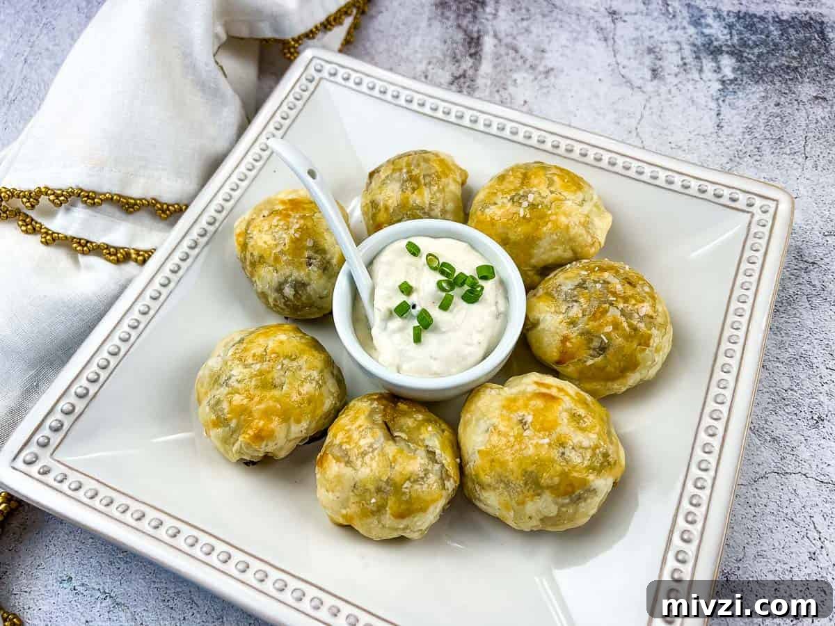 37 Winter Olympics Dishes to Warm Cold Nights and Long Broadcasts 22 Beef Wellington Bites on a white plate with sauce in the middle.