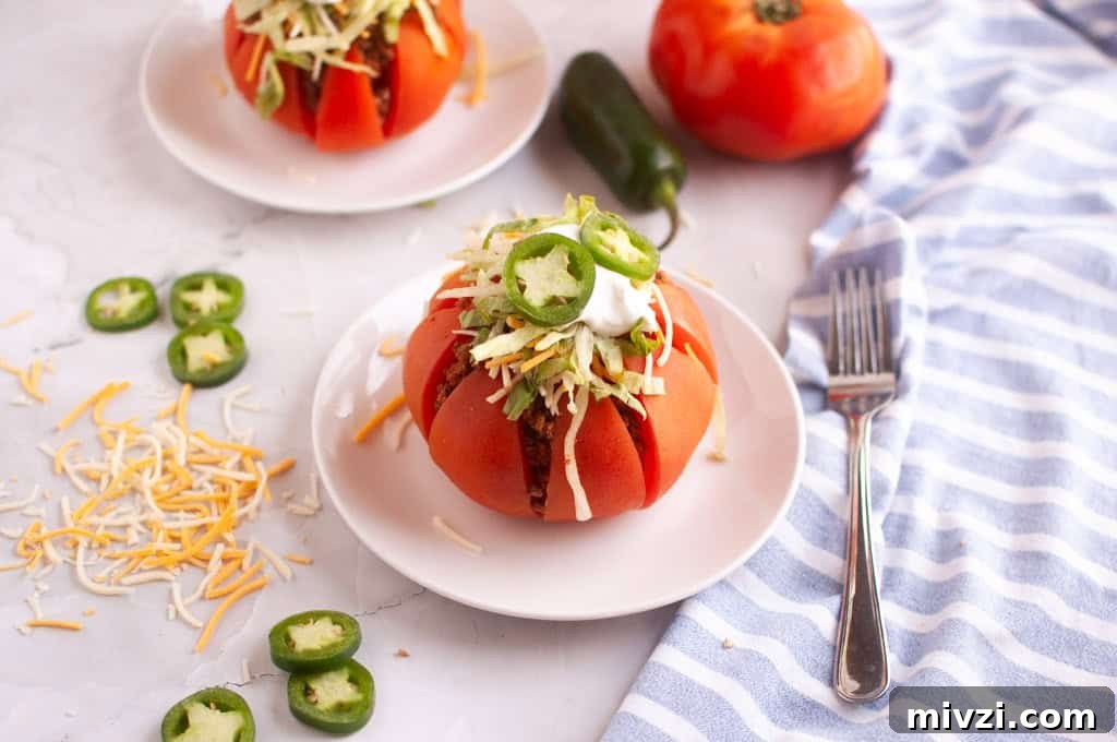37 Winter Olympics Dishes to Warm Cold Nights and Long Broadcasts 23 Two taco stuffed tomatoes on white plates with toppings and a fork.