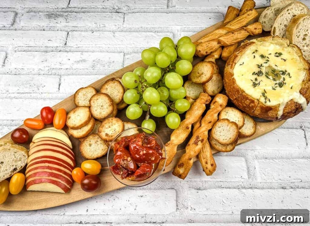 37 Winter Olympics Dishes to Warm Cold Nights and Long Broadcasts 24 A wooden platter with baked brie in a bowl, cheese, crackers, grapes and bread.