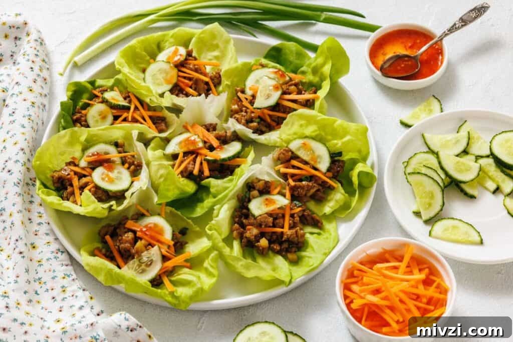 37 Winter Olympics Dishes to Warm Cold Nights and Long Broadcasts 25 A plate of chicken lettuce wraps filled with shredded carrots and cucumber slices, with bowls of sliced cucumbers, shredded carrots, and dipping sauce on the side.