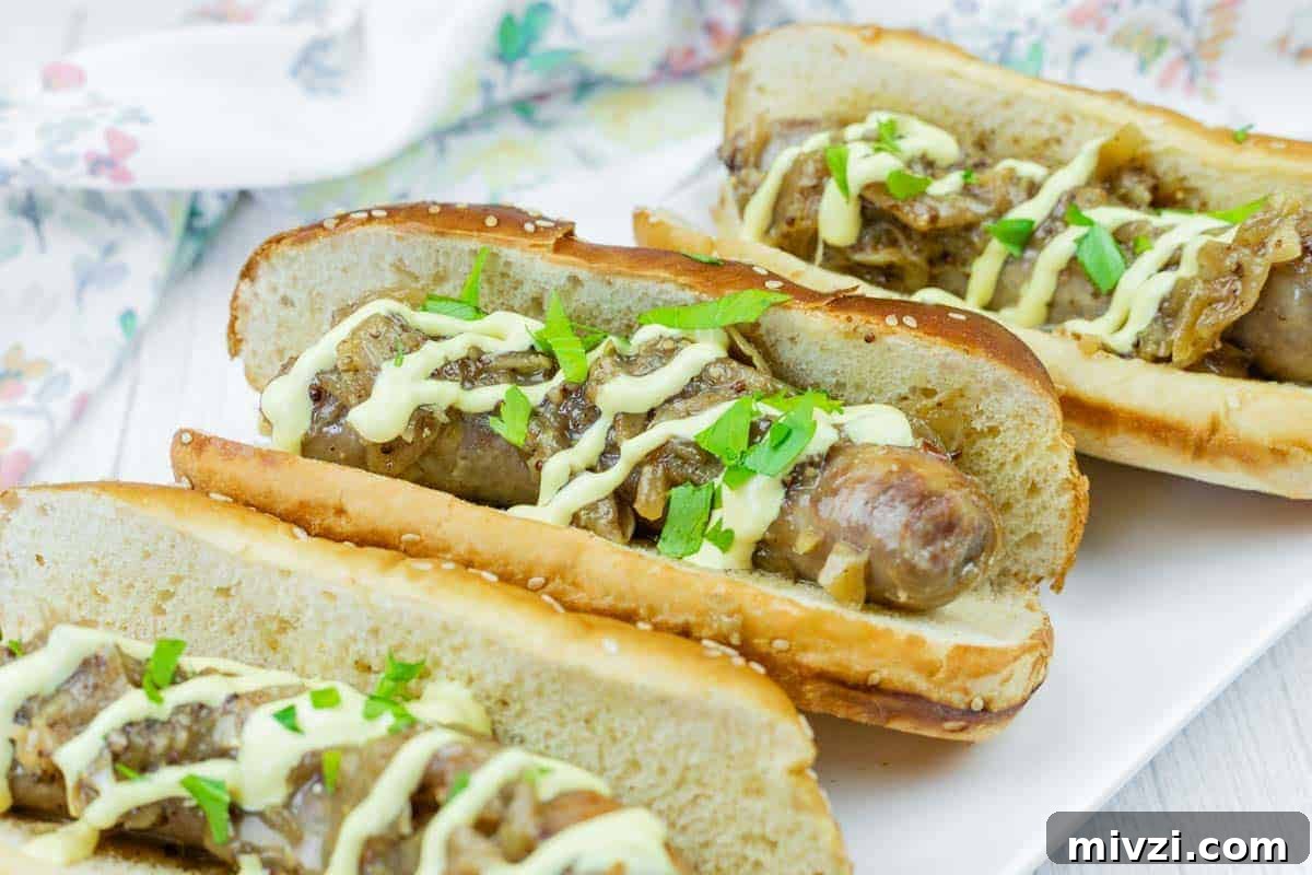 37 Winter Olympics Dishes to Warm Cold Nights and Long Broadcasts 32 Three Beer Braised Brats in toasted buns topped with sautéed onions, chopped parsley, and a drizzle of yellow sauce, served on a white plate.
