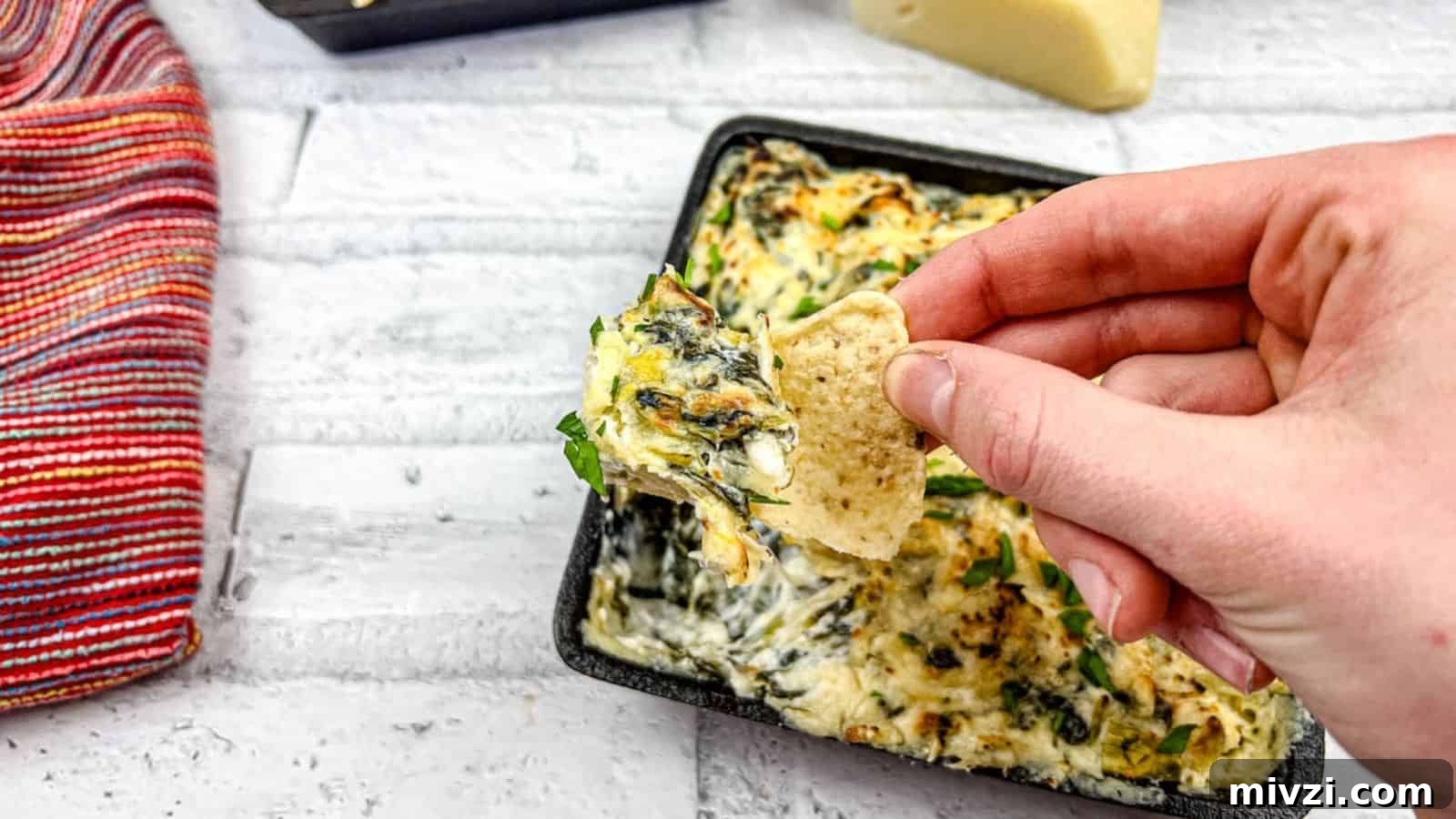37 Winter Olympics Dishes to Warm Cold Nights and Long Broadcasts 39 A hand dipping a tortilla chip into a tray of Copycat Applebee’s spinach artichoke dip.
