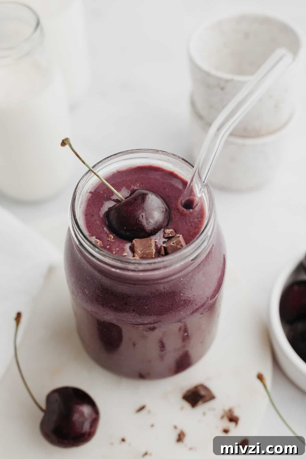 5-Minute Chocolate Cherry Smoothie Recipe 2 A chocolate cherry smoothie in a glass jar, it is topped with a fresh cherry.