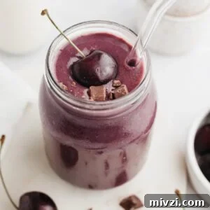 5-Minute Chocolate Cherry Smoothie Recipe 10 A chocolate cherry smoothie in a glass jar, it is topped with a fresh cherry.