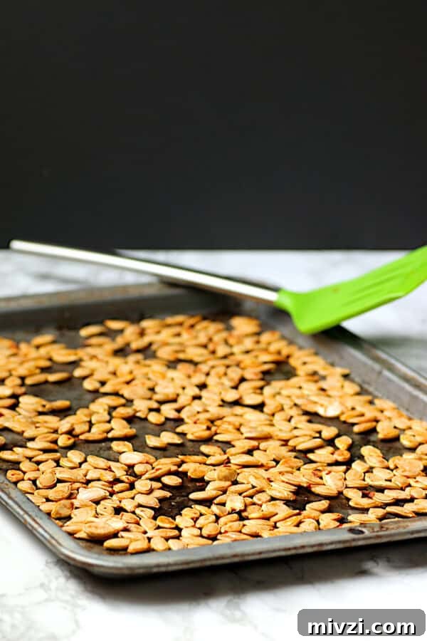 Roasted Pumpkin Seeds Recipe: Crispy Oven-Baked Snack in 20 Minutes 2 Homemade roasted pumpkin seeds on a baking sheet.