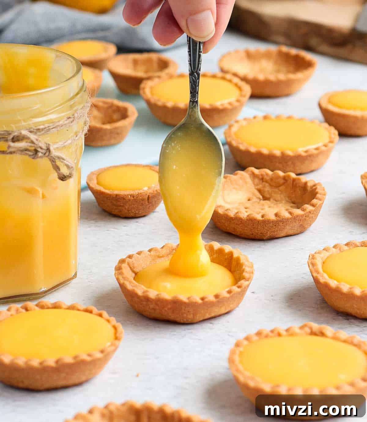 Pouring the lemon curd inside a tartlet shell.