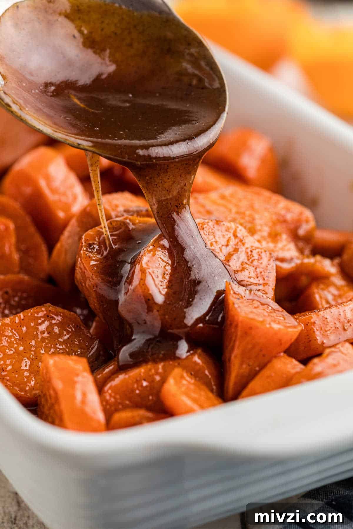 Southern-Style Candied Yams with Brown Sugar Glaze 2 A dish full of candied yams with a treacle being poured over the top.