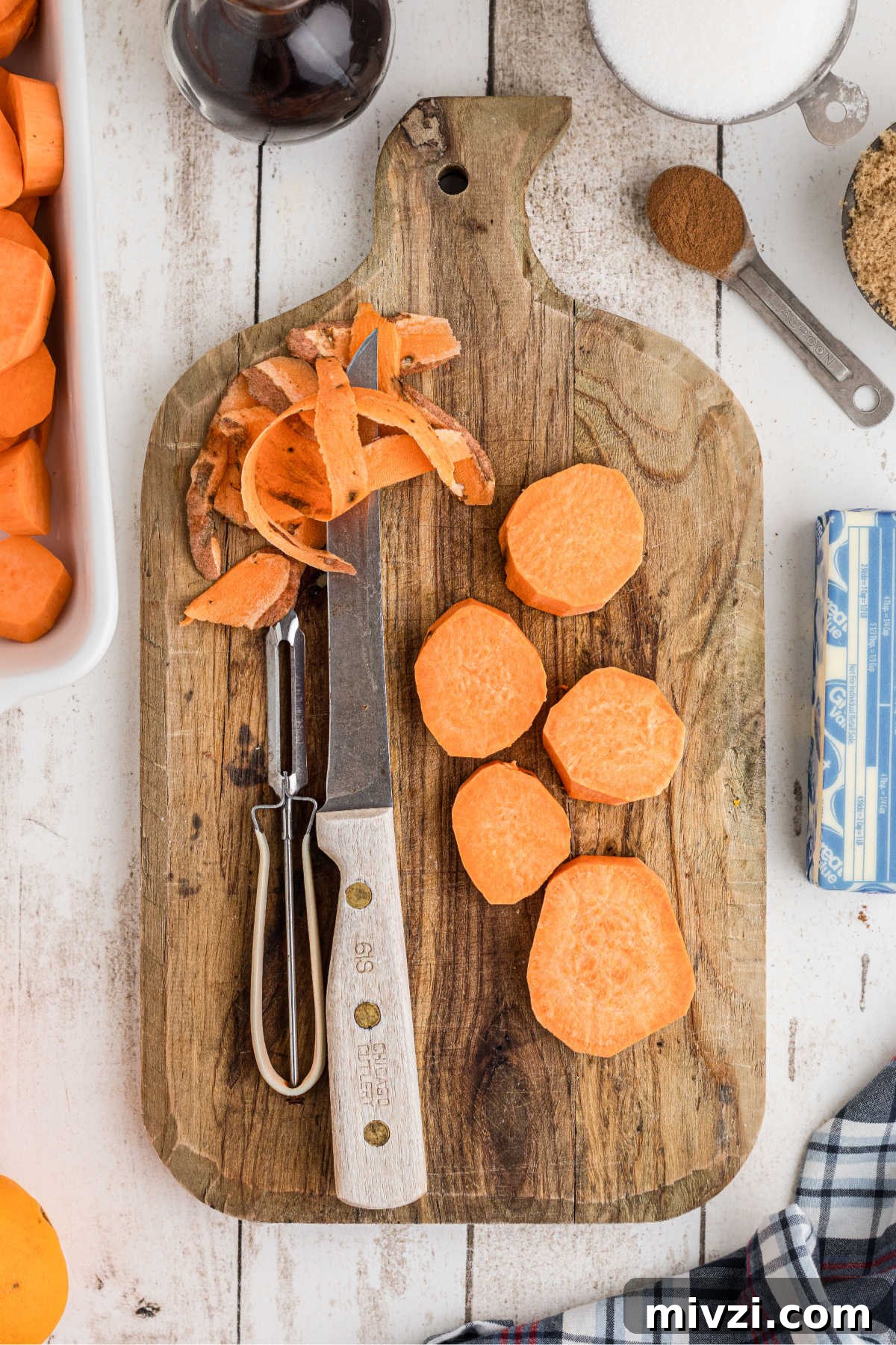 Southern-Style Candied Yams with Brown Sugar Glaze 4 A cutting board with some yams being peeled and sliced.