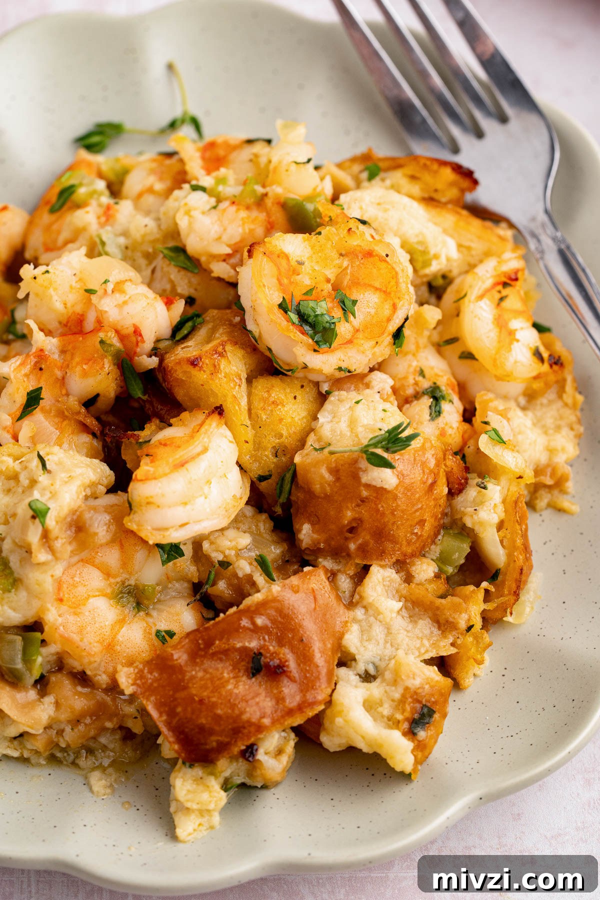 Savory Seafood Stuffing Recipe for Holidays and Dinner 5 A big scoop of seafood stuffing sits on a plate with a fork to the side.