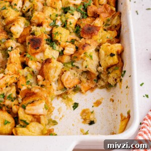Savory Seafood Stuffing Recipe for Holidays and Dinner 6 A baking dish with baked seafood stuffing with a scoop removed.