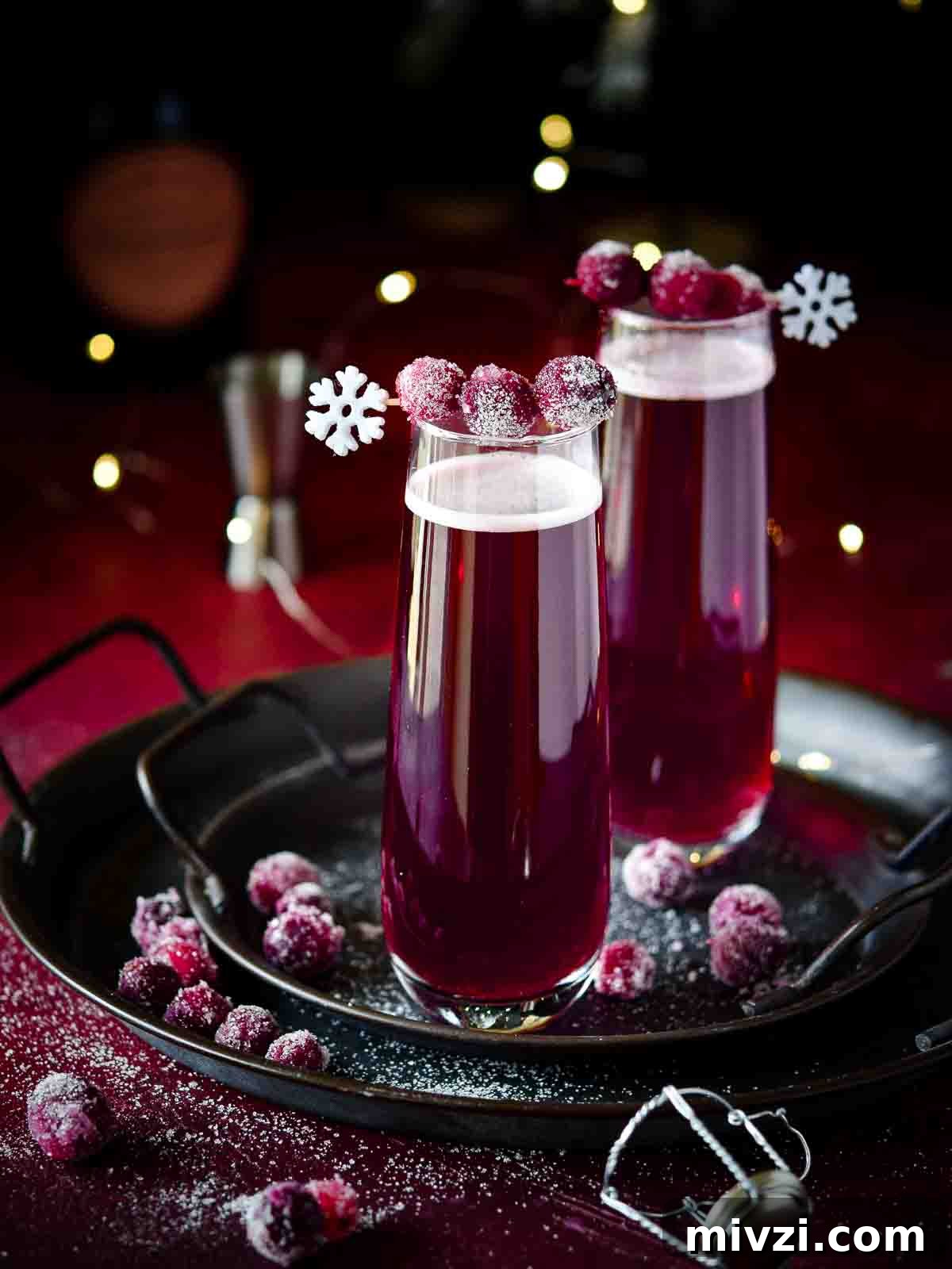 Cranberry mimosas with sugared cranberries on a black tray.