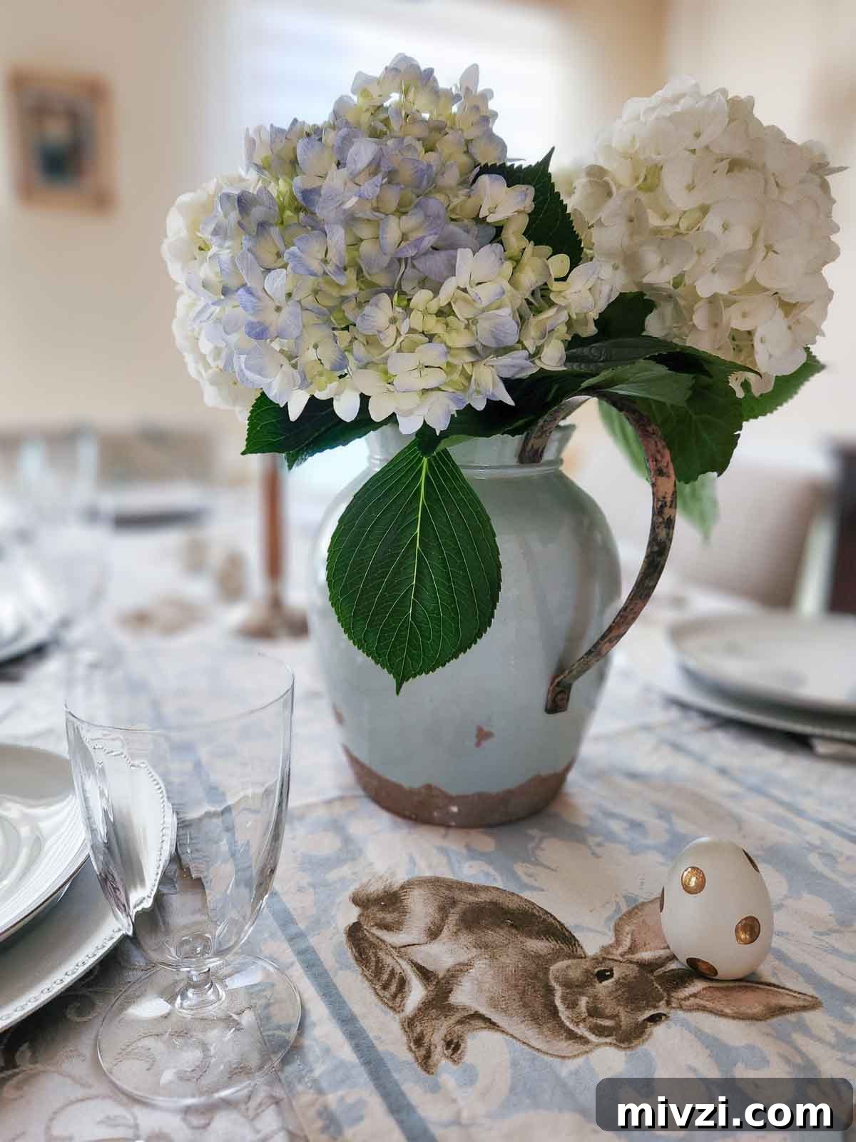 An Easter table decorated with hydrangeas, easter eggs, and a blue rabbit runner.