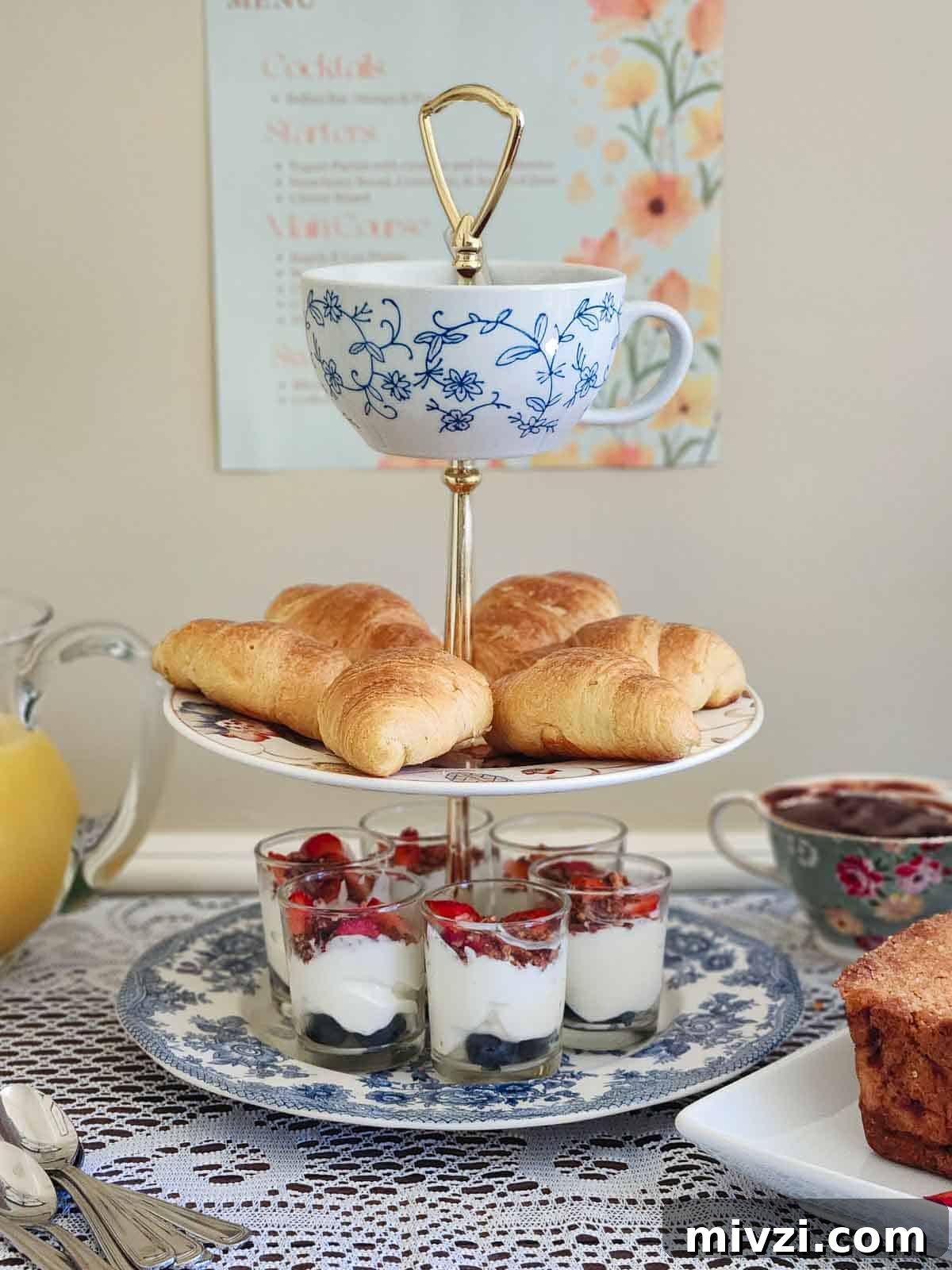 Charming tea display featuring croissants, layered desserts, and a floral teacup.