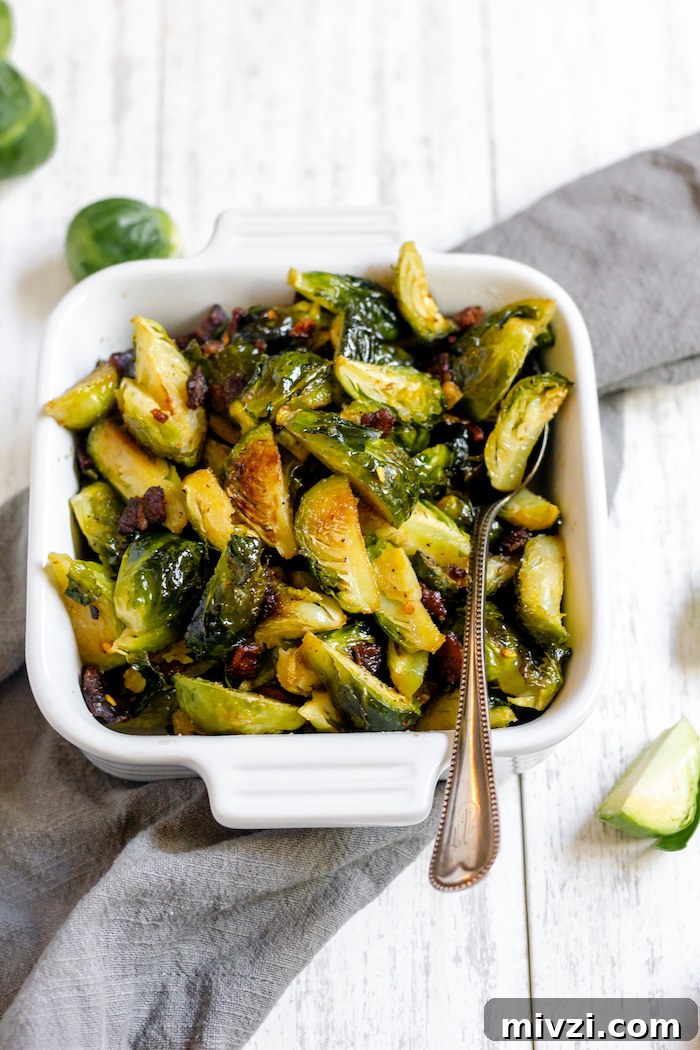 Image shows a pan of roasted brussels sprouts with a spoon