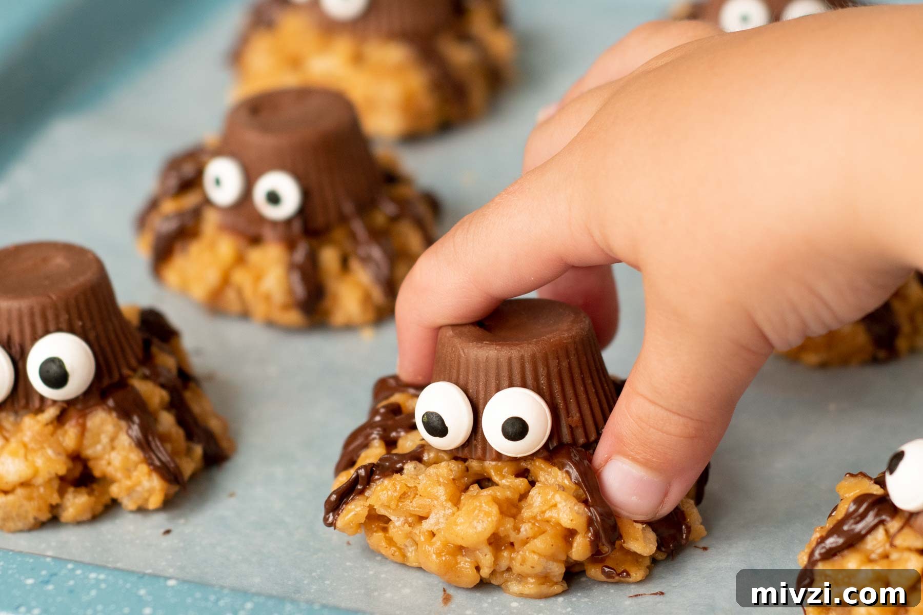 a kid's hand picking up a spider cookie