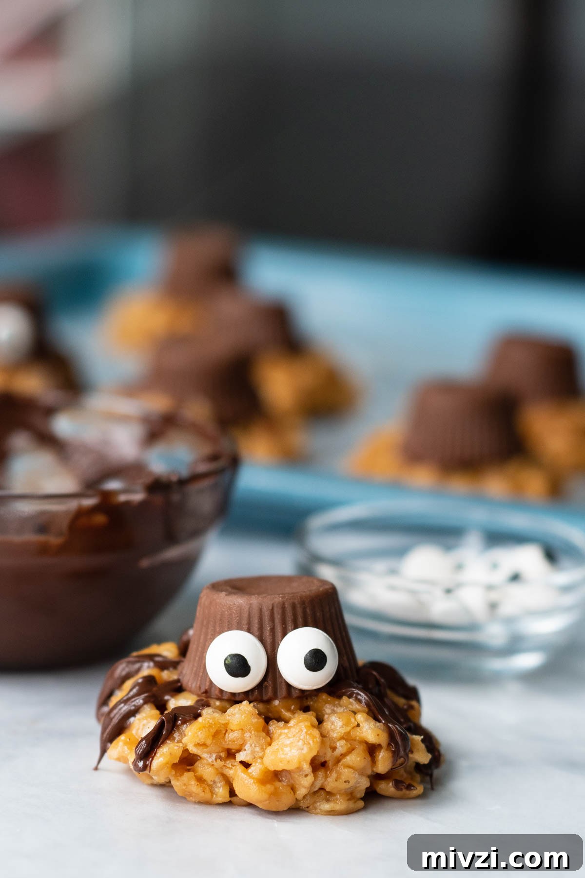 a spider cookie facing camera with some more on a baking sheet in the background