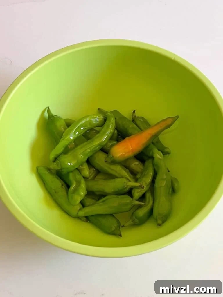 Peppers in a green bowl tossed in oil.