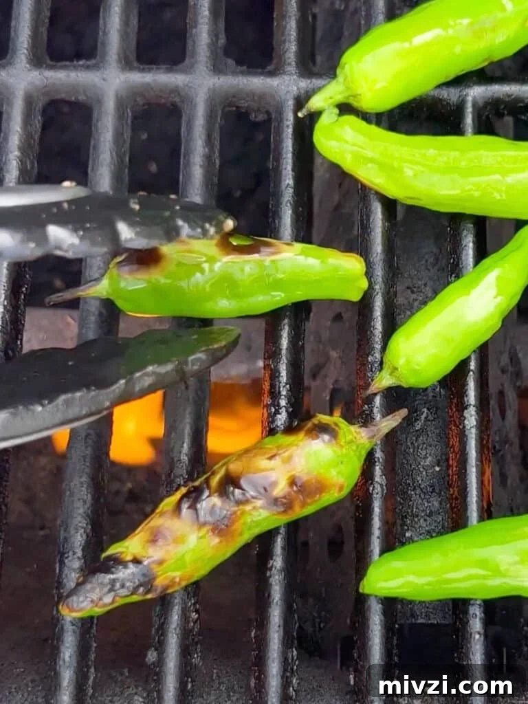 Blistered shishito peppers on the grill being turned and blistered.