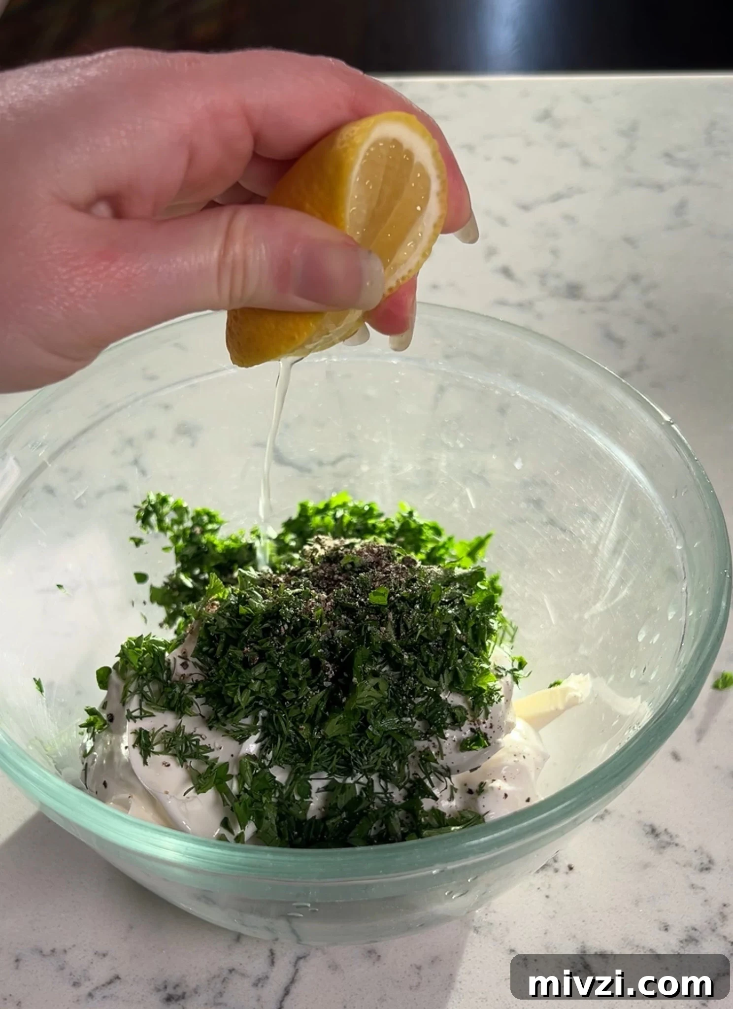 Adding lemon juice to the dip mixture.
