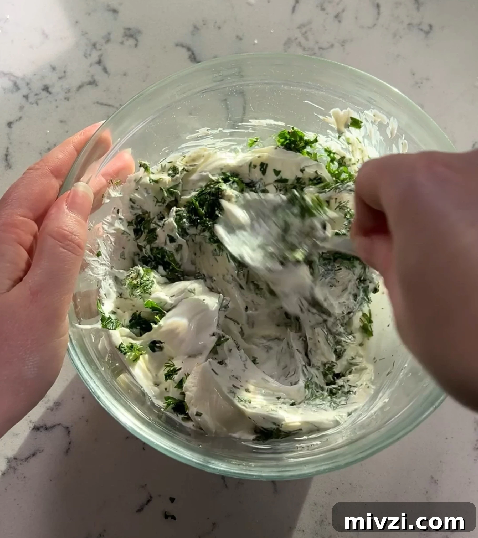 Mixing together the herbs and sour cream and cream cheese.