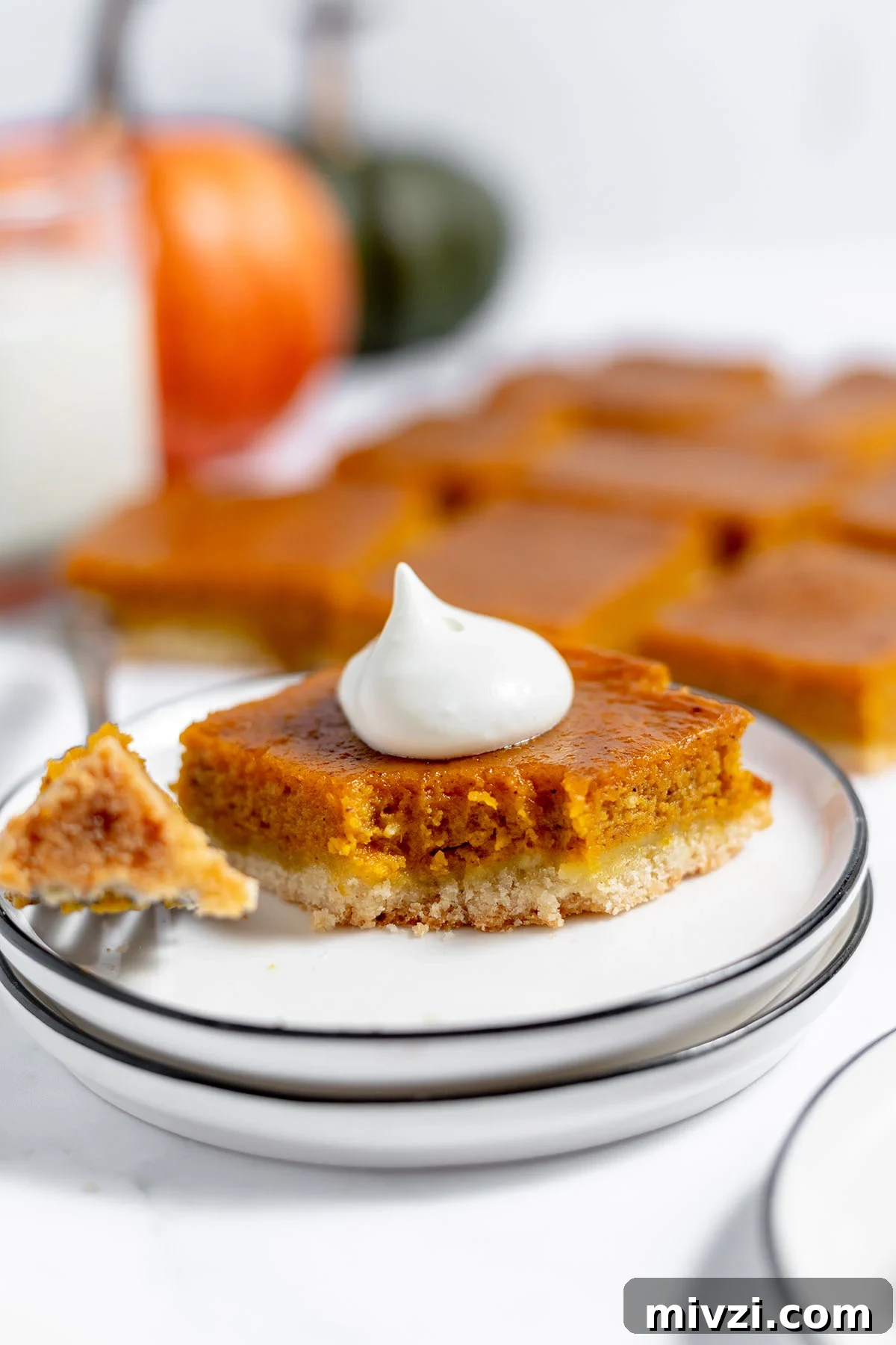Creamy Pumpkin Pie Bars with Gingersnap Crust — Fall Dessert Recipe 11 Slice of Pumpkin Pie Bar on a plate, topped with whipped cream with a bite on a fork.