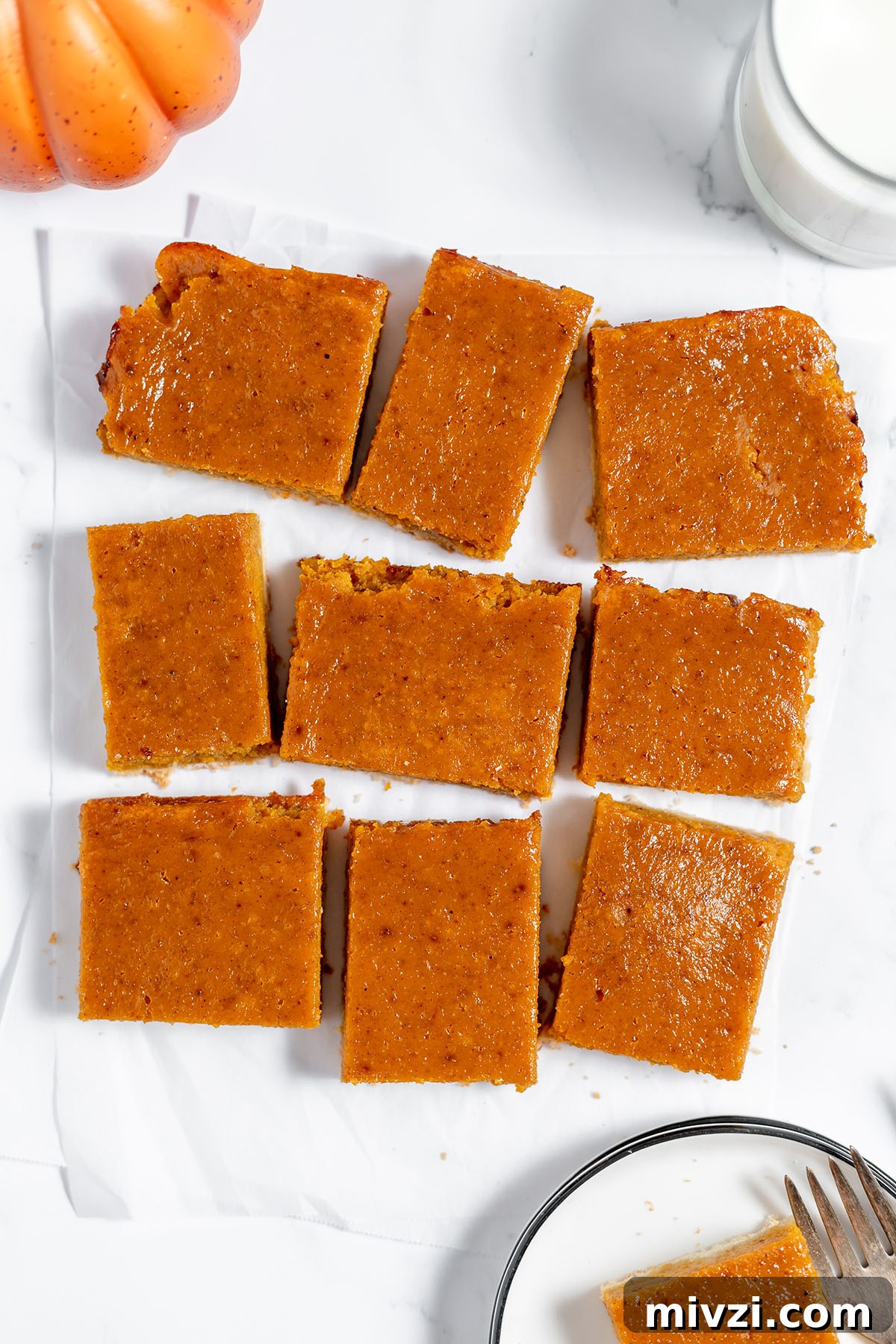 Creamy Pumpkin Pie Bars with Gingersnap Crust — Fall Dessert Recipe 10 Nine slices of Pumpkin Pie Bar on parchment paper.