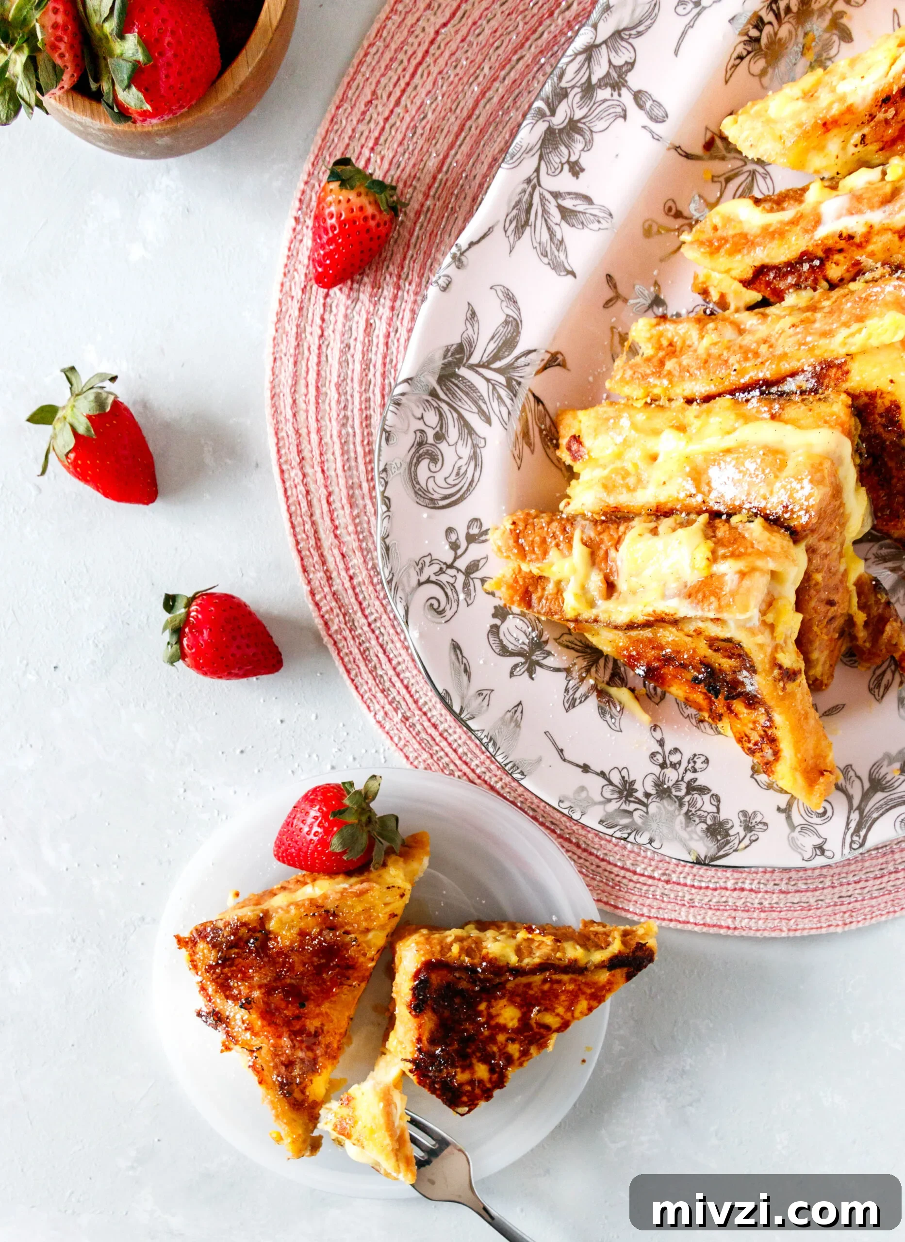 Crème Brûlée French Toast Recipe: Custardy, Caramelized Breakfast 3 top view of the stuffed french toast on a platter, with a single serving on a plate. Scattered strawberries are on the table