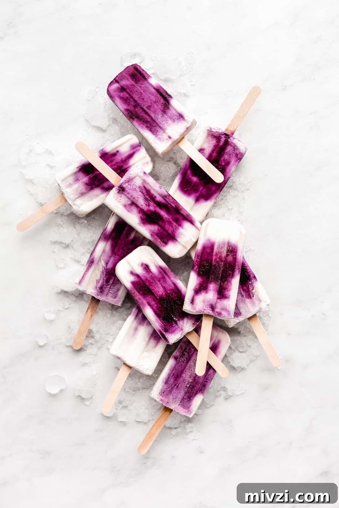 Blueberry Greek Yogurt Popsicles Recipe: Creamy Frozen Treats 2 blueberry greek yogurt popsicles stacked on ice on a marble board