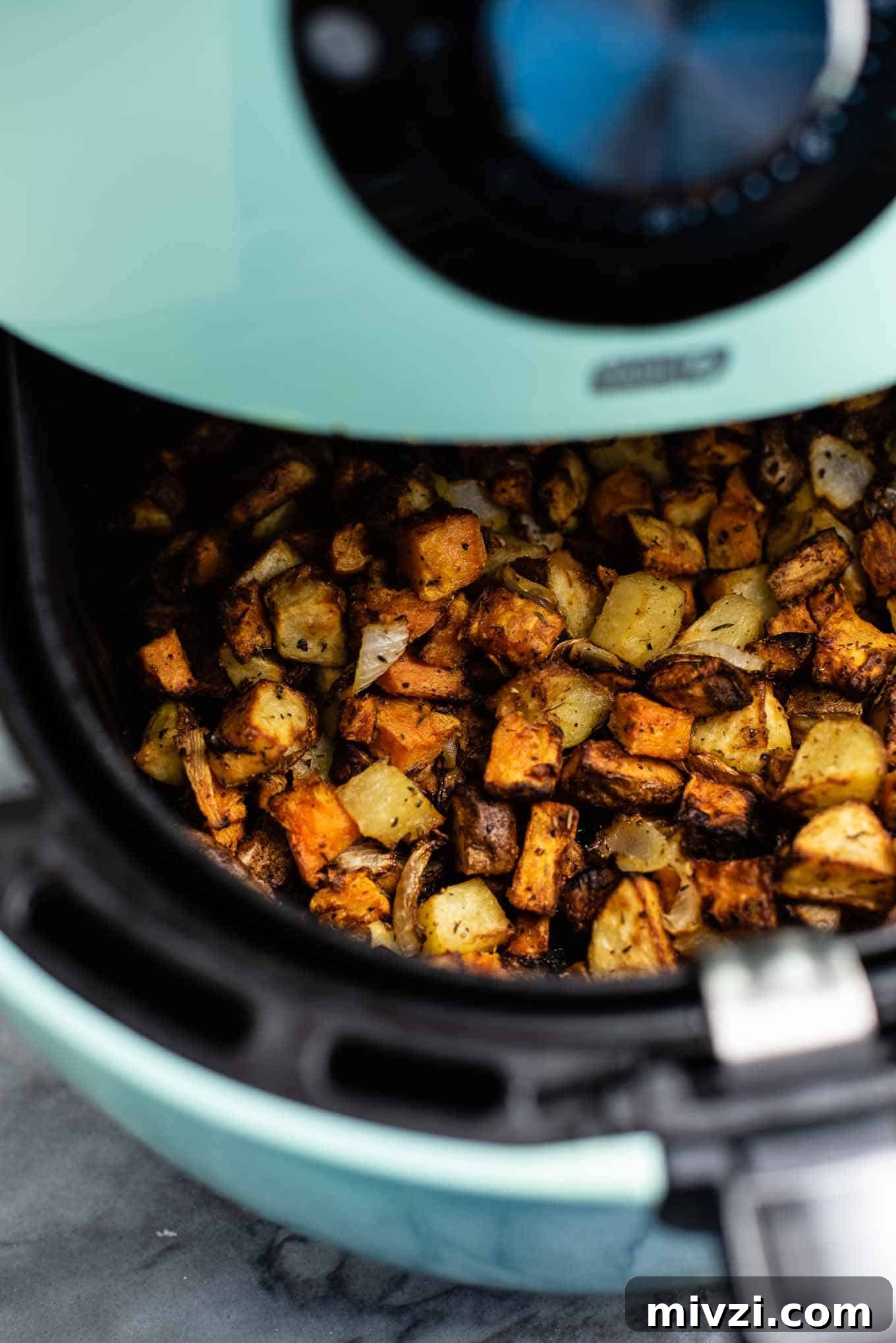 Crispy Air Fryer Breakfast Potatoes Recipe 7 hash in an air fryer basket being pulled out