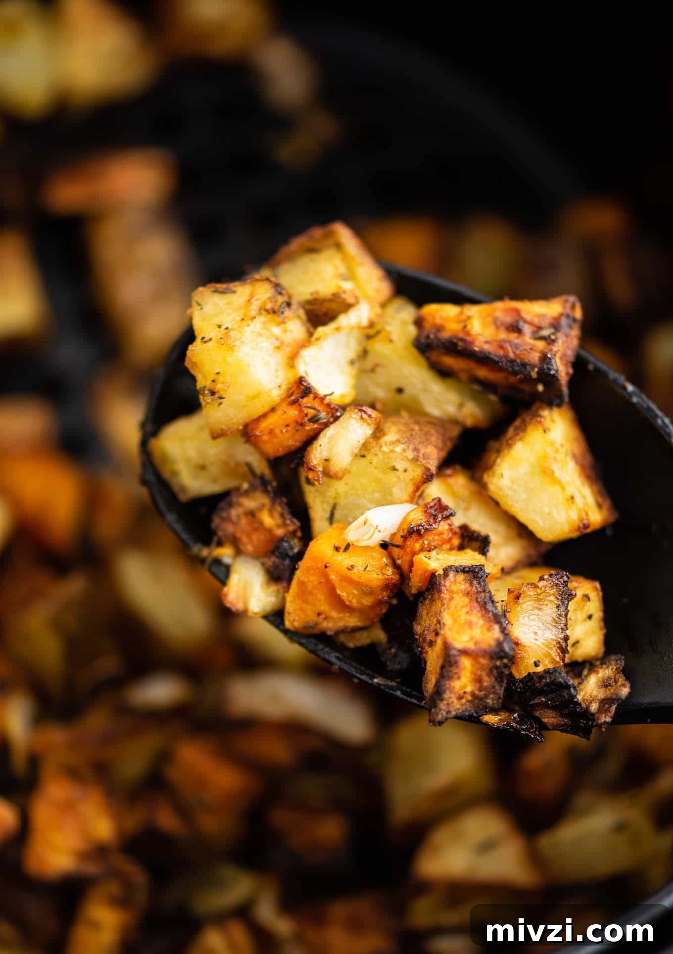 Crispy Air Fryer Breakfast Potatoes Recipe 9 sweet potatoes, russet potatoes, and onions on a black spoon